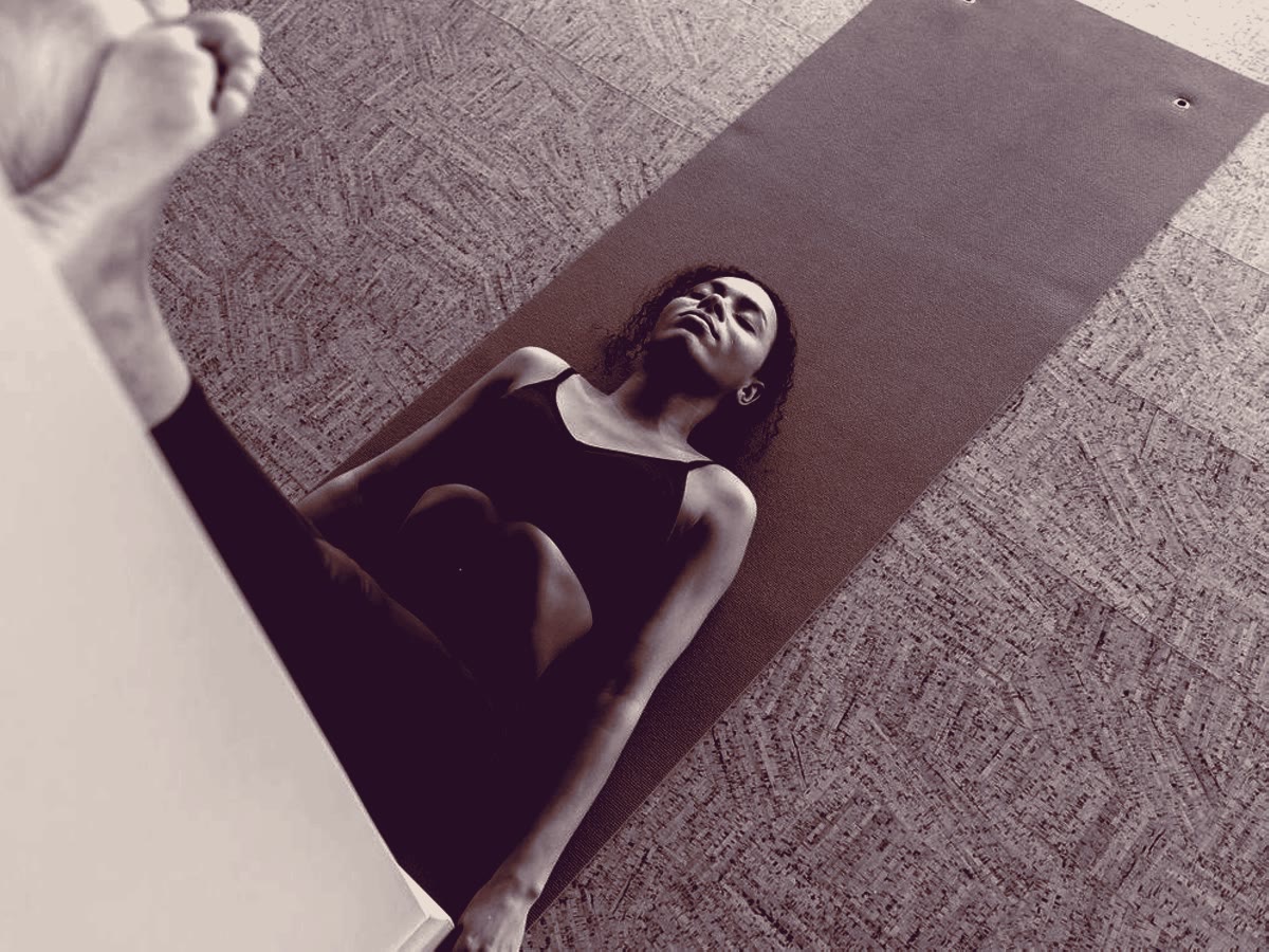 Someone resting on a mat with their legs up a wall