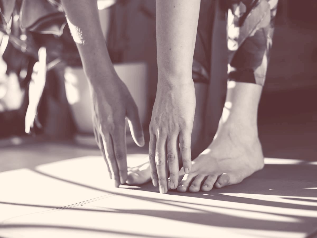 Hands reaching to bare feet in morning light