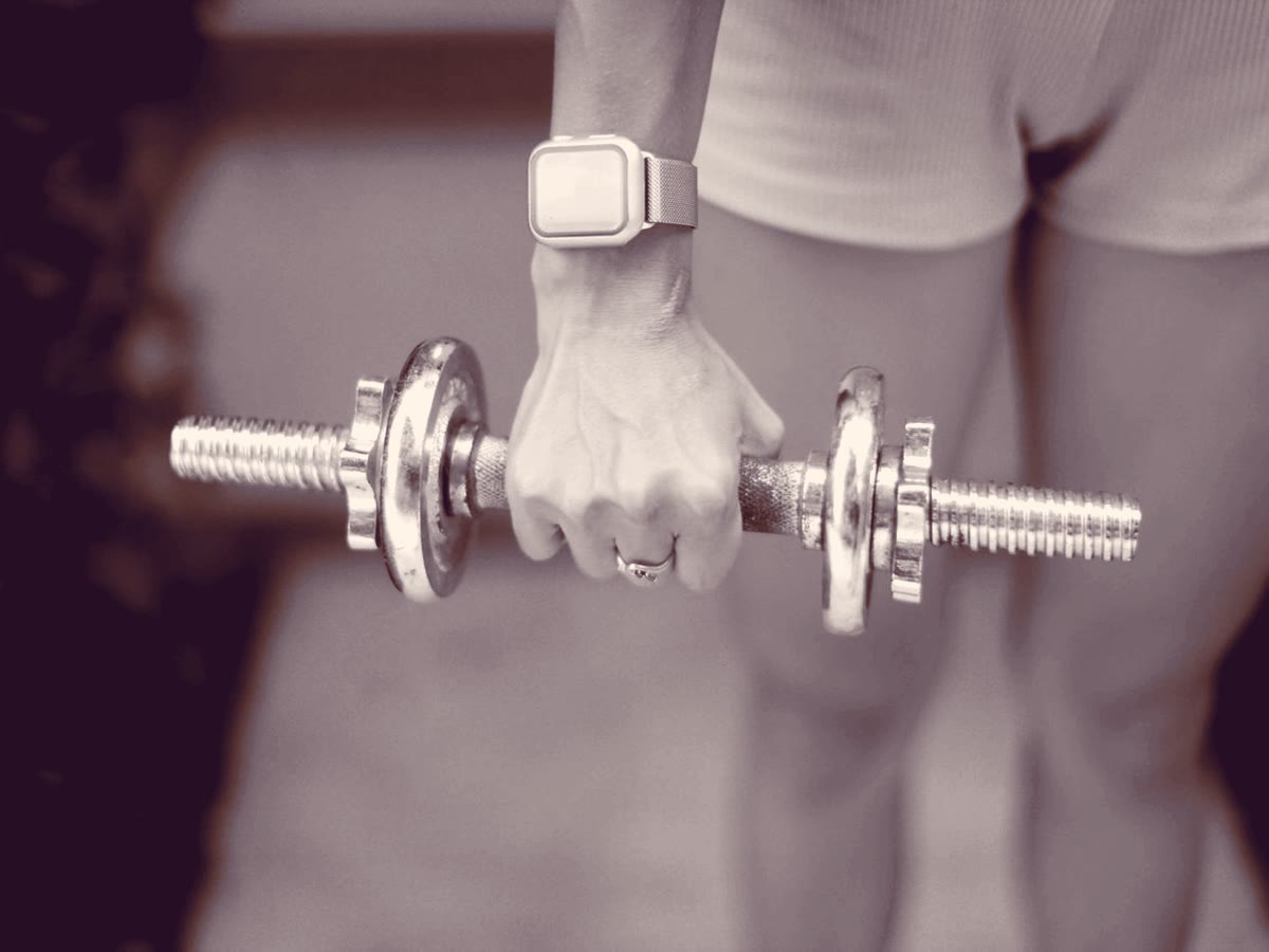 A hand gripping a dumbbell, a smartwatch on the wrist